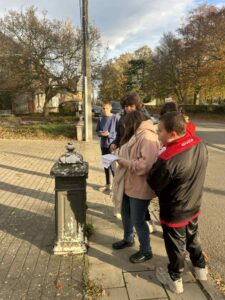 Des enfants avec leur enseignante devant une boîte aux lettres